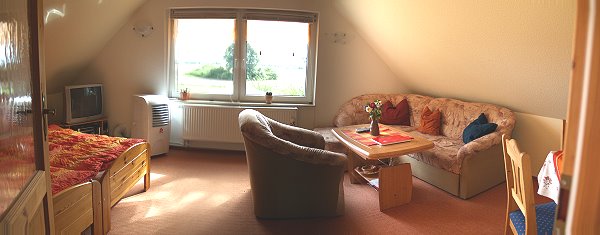 Weitwinkelaufnahme des Wohnzimmers der Ferienwohnung: Blick aus dem Flur ins Wohnzimmer
